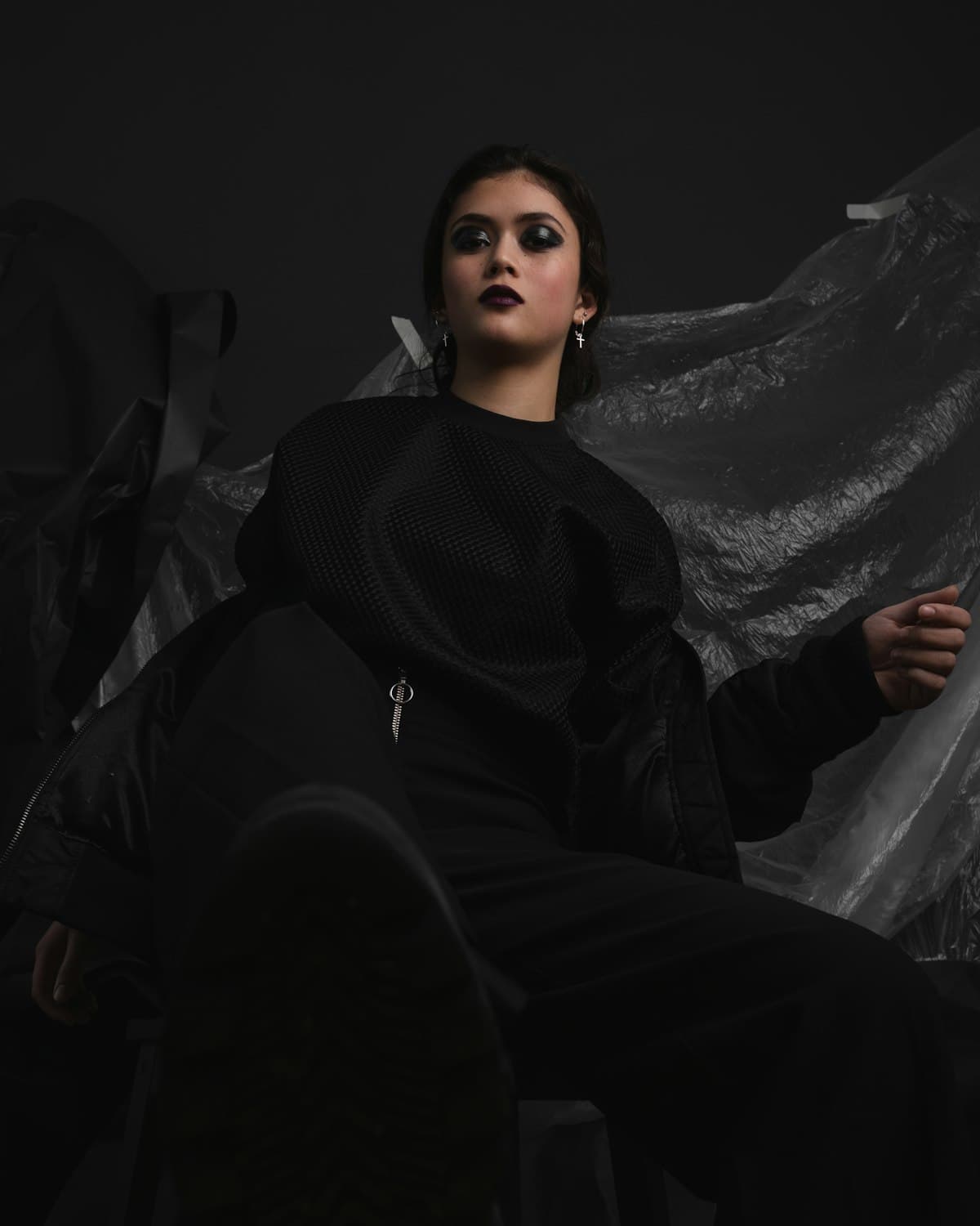 Woman in all-black streetwear seated in low light