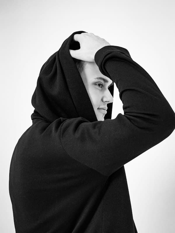 Man pulling up the hood of a black hoodie